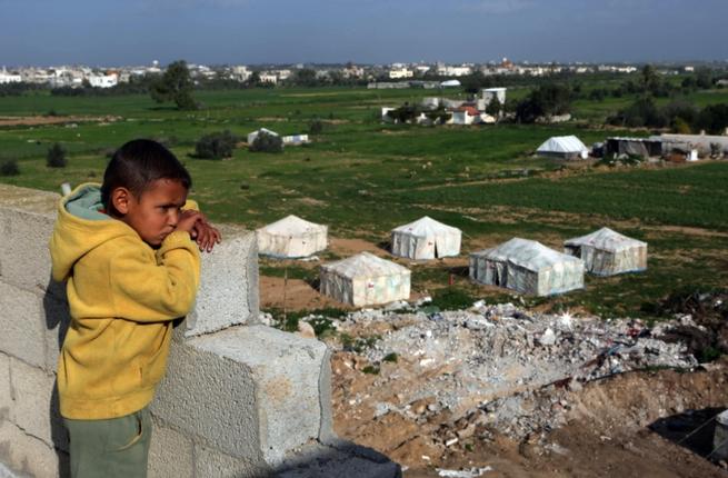 A young Palestinian boy looks out over the rubble that used to be his home