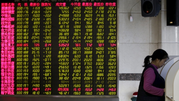 An investor checks stock information on a computer next to an electronic board at a brokerage house in Beijing on Friday