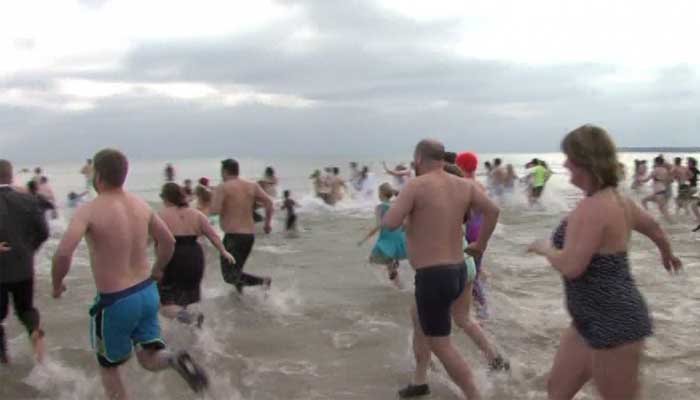 Hundreds of people take a dip into the icy waters of Lake Michigan on Friday