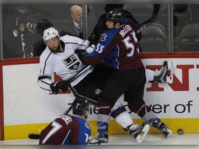 Colorado Avalanche left wing Cody McLeod back right knocks Los Angeles Kings defenseman Jake Muzzin,left of his skates with a check as Avalanche center John Mitchell front looks on Monday in Denver