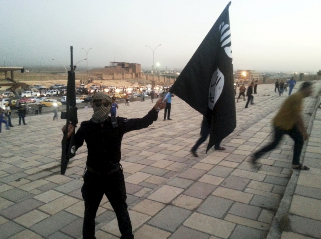 ISIL holding a flag and a weapon on a street in Mosul