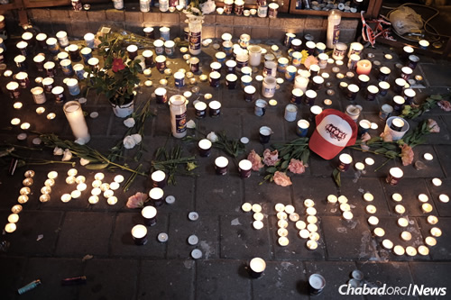 Israelis light candles on Saturday night spelling out the names of victims “Shimi and Alon” outside a pub on Dizengoff Street in central Tel Aviv