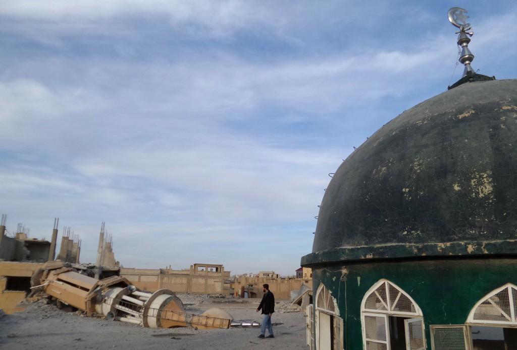 A man walks past a damaged mosque after what activists said were airstrikes by forces loyal to Syria's President Bashar al Assad in Raqqa eastern Syria which is controlled by the Islamic State on Nov. 25 2014