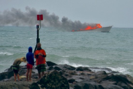 People stand on the shoreline as a tourist boat carrying 60 people burns out at sea off the coast of Whakatane New Zealand