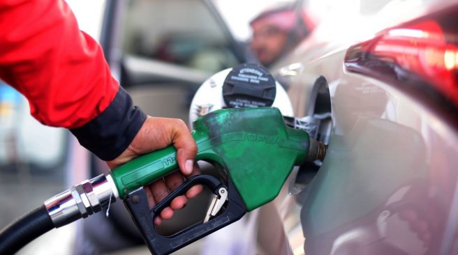 Saudi employee fills the tank of his car with petrol at a station