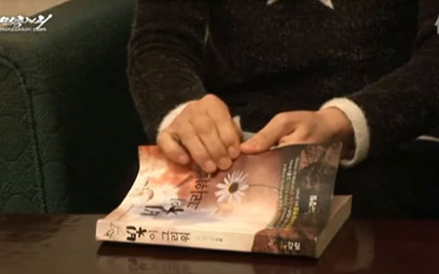 Son Ok Sun prepares to destroy a copy of her book