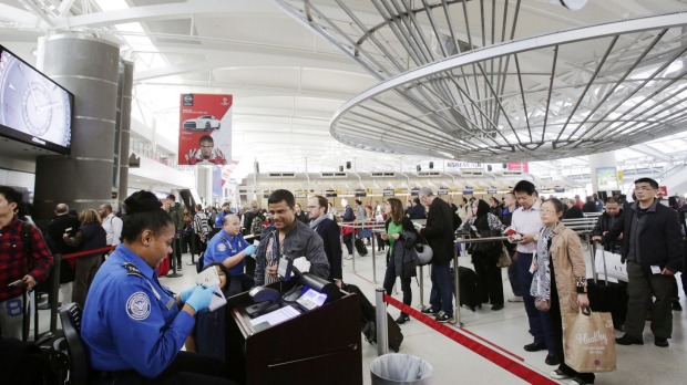 A Transportation Security Administration officer left checks a passenger's ticket boarding pass and passport as part of security screening at John F. Kennedy International Airport in New York