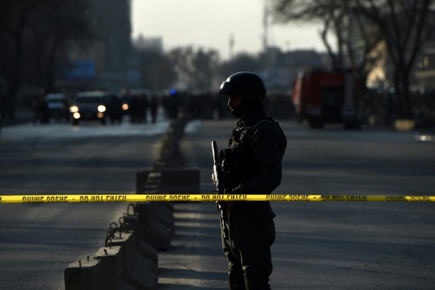 An Afghan security personnel stands guard near the site of a suicide attack at the entrance to a police base in Kabul