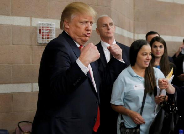 Republican U.S. presidential candidate Donald Trump flexes his muscles as he talks with caucus participants while visiting a Nevada Republican caucus site at Palo Verde High School in Las Vegas Nevada