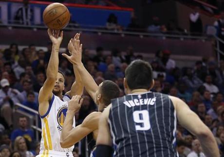 Feb 25 2016 Orlando FL USA Golden State Warriors guard Stephen Curry shoots a 3 point basket over Orlando Magic center Nikola Vucevic and forward Aaron Gordon during the second half of a basketball game against the Orlando Magic at Amwa