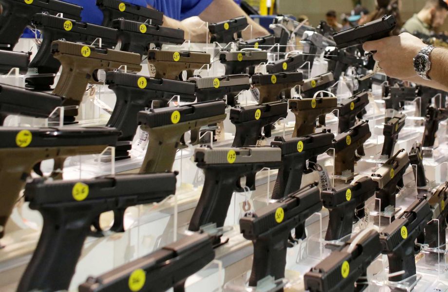 FILE- A customer looks at a pistol at a vendor's display at a gun show held by Florida Gun Shows in Miami on Saturday Jan. 9 2016. States enter data into the national background check system about people who are convicted of crimes that disqualify them