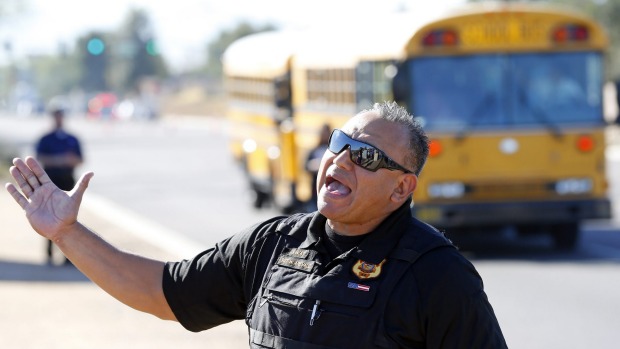 A police officer tries to give instructions to parents waiting to reunite with their children in Glendale Arizona after