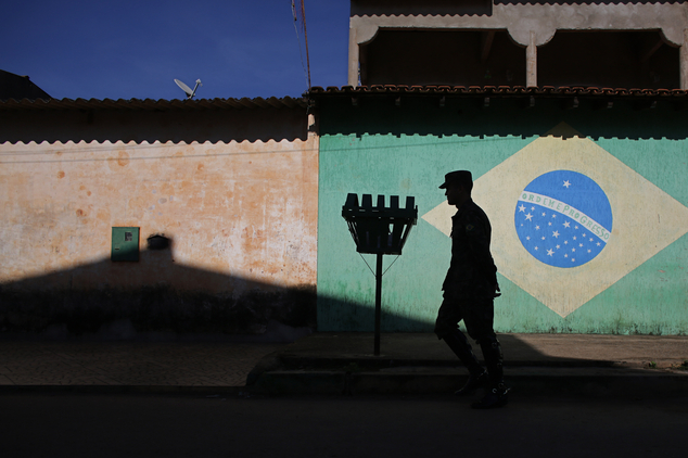 An army soldier walks in in front of a mural of the Brazilian flag during an operation to eradicate Aedes aegypti mosquito breeding sites in the Brazlandia