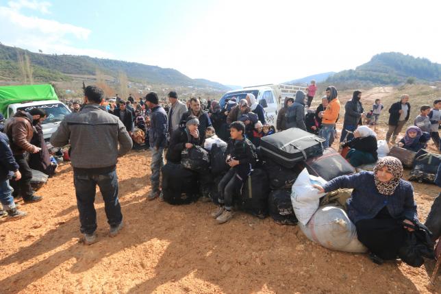 Internally displaced Syrians fleeing advancing pro-government Syrian forces wait near the Syrian Turkish border after they were given permission by the Turkish authorities to enter Turkey in Khirbet Al-Joz Latakia countryside