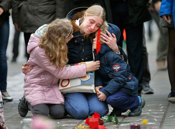 A woman consoles her children at a street memorial following Tuesday’s bomb attacks in Brussels on Wednesday