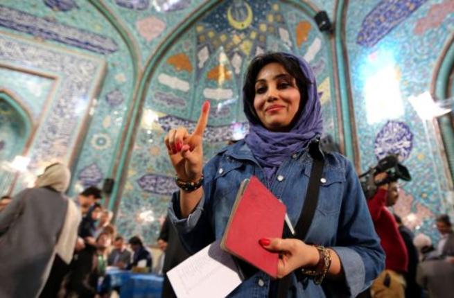 An Iranian woman voting in Iran's elections shows her inked finger after casting her ballot at a polling station in Tehran