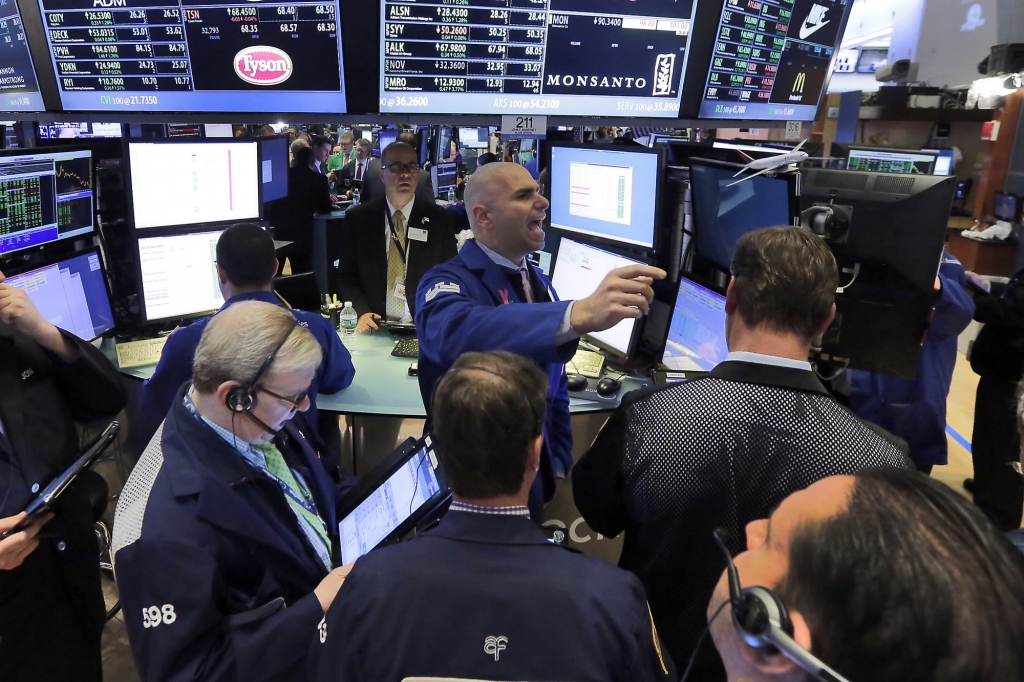 Specialist Philip Finale background center works with traders at the post that handles Monsanto on the floor of the New York Stock Exchange Thursday