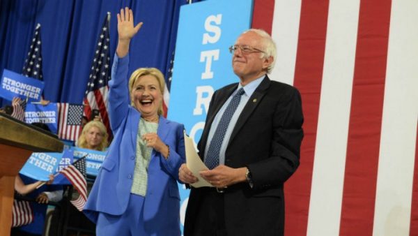 Darren McCollester Getty Images North America AFP | Presumptive Democratic presidential nominee Hillary Clinton and Bernie Sanders take the stage at Portsmouth High School in New Hampshire