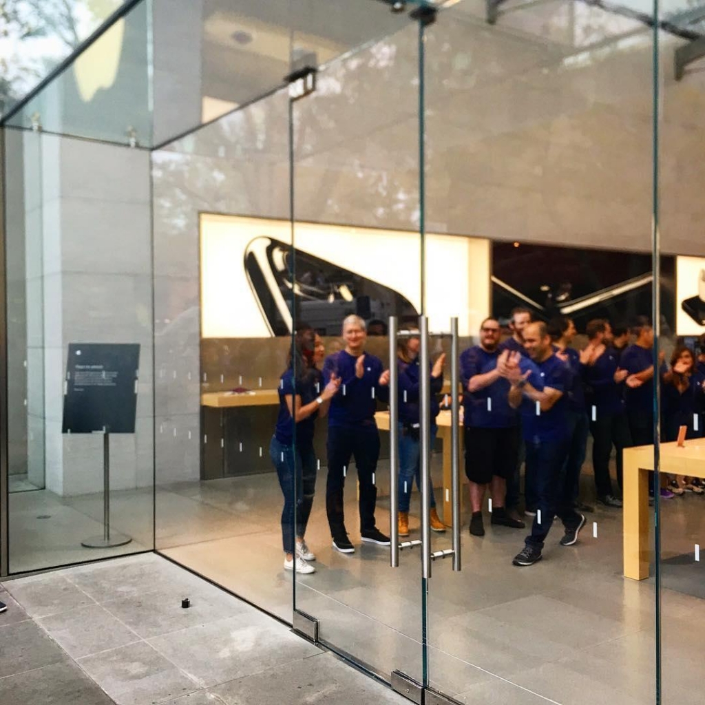 Apple CEO Tim Cook stands with other employees as the store in Palo Alto prepares to greet the first customer in line at the start of sales of the new iPhone 7