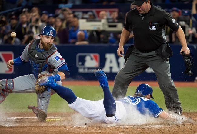 Toronto Blue Jays third baseman Josh Donaldson scores the game-winning run past Texas Rangers catcher Jonathan Lucroy during tenth inning American League Division Series action in Toronto on Sunday