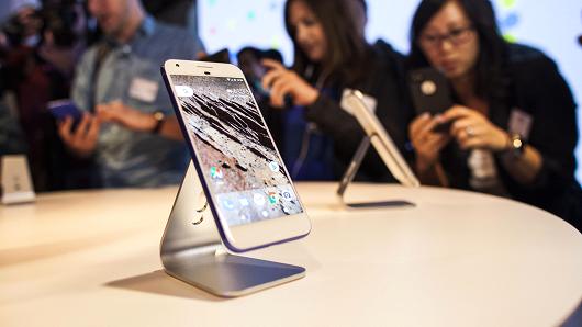 Members of the media examine Google's Pixel phone during an event to introduce Google hardware products