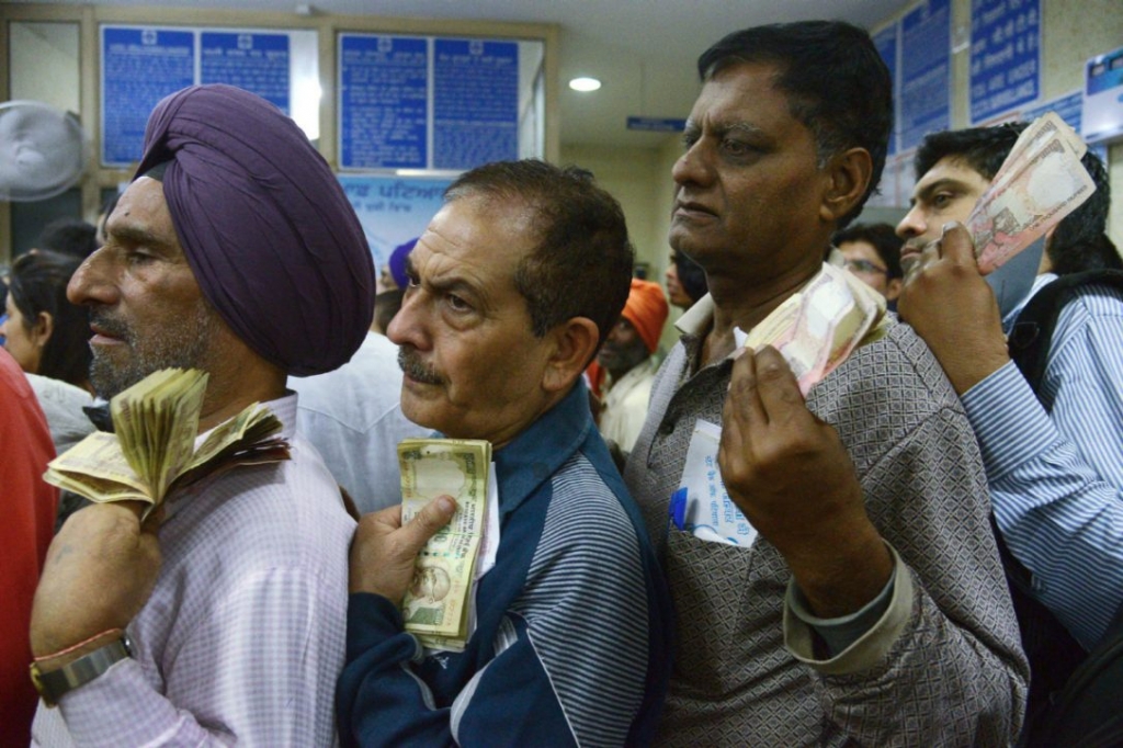 Indian bank customers wait to deposit 500 and 1,000 Indian currency notes at a bank in the city of Amritsar