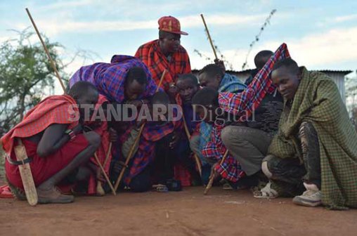 Maasai youths follow the US presidential election updates over the radio yesterday