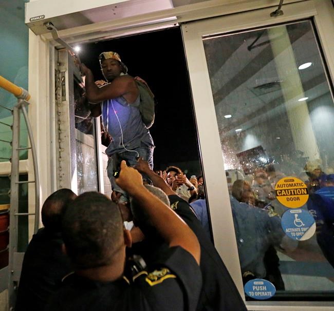 A police officer front points a taser as a protester jumps on a door whole police officers try to keep out protesters against the former Ku Klux Klan leader and current senate candidate David Duke before a debate for Louisiana candidates for the U.S