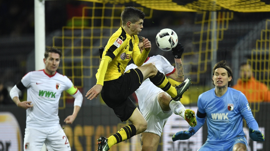 Dortmund's Christian Pulisic jumps for the ball in front of Augsburg goalkeeper Marwin Hitz during the German Bundesliga soccer match between Borussia Dortmund and FC Augsburg in Dortmund Germany Tuesday Dec. 20 2016