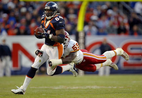 Tight end Shannon Sharpe #84 of the Denver Broncos drags along linebacker Shawn Barber #59 of the Kansas City Chiefs