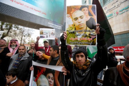 A Palestinian holds a poster of Israeli Sergeant Elor Azaria that reads