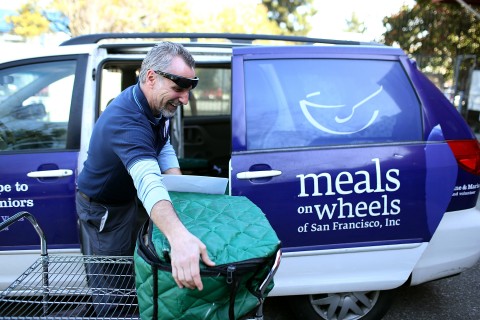 Meals on Wheels of San Francisco driver Jim Fleming loads meals into a van before making deliveries in 2013