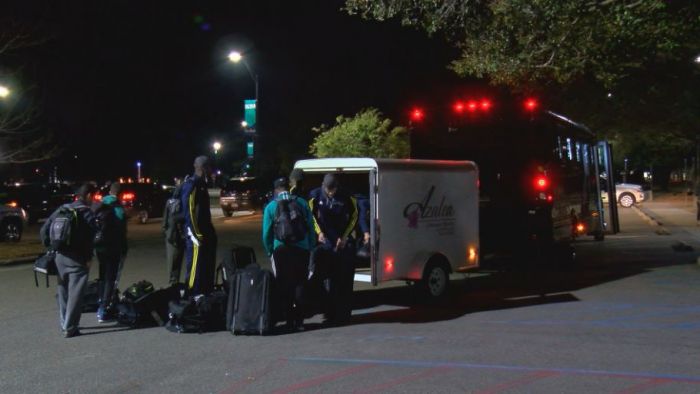 Members of the UNCW men's basketball team unloading their gear after returning home from the NCAA tournament game in Orlando