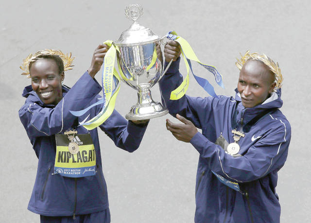 Edna Kiplagat left and Geoffrey Kirui both of Kenya hold a trophy together after their victories in the 121st Boston Marathon Monday