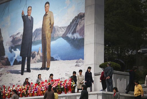 North Koreans offer flowers in front of a mural of late leaders Kim Il Sung left and Kim Jong Il on Friday