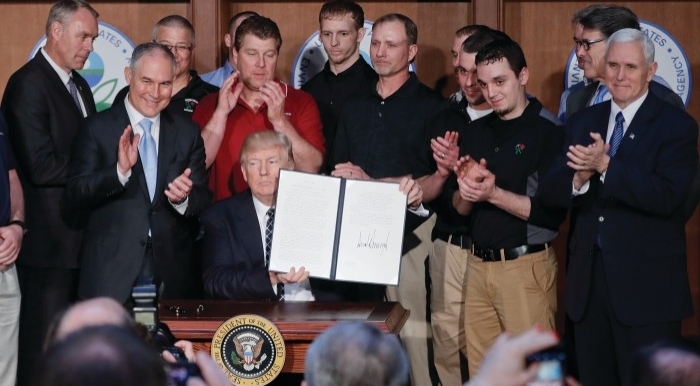 Donald J. Trump holding up an executive order he signed