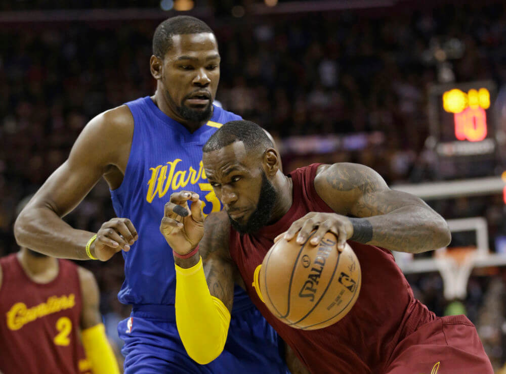 Cleveland Cavaliers&#039 Le Bron James drives past Golden State Warriors&#039 Kevin Durant in the first half of an NBA basketball game in Cleveland. From Cleveland to Oakland the two star-studded team