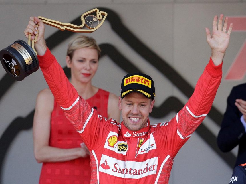 Ferrari’s Sebastian Vettel celebrates winning the race on the podium with the trophy./REUTERS