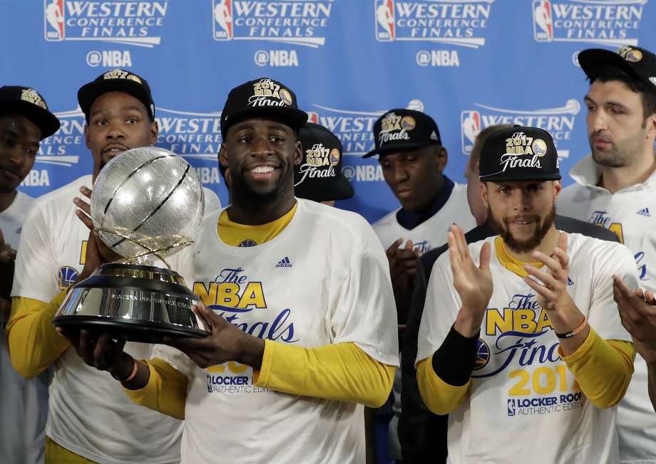 Golden State Warriors Draymond Green carries the trophy as Kevin Durant left rear and Stephen Curry front right cheer after their 129-115 win over the San Antonio Spurs during the second half in Game 4 of the NBA basketball Western Conference finals