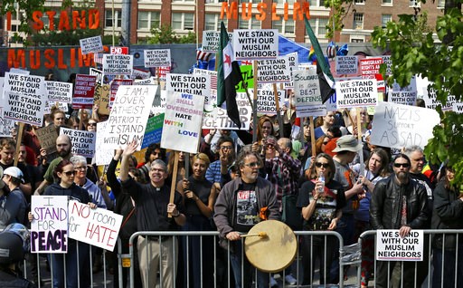 Counter-protestors stand behind barricades across the street from an anti Islamic law protest rally Saturday