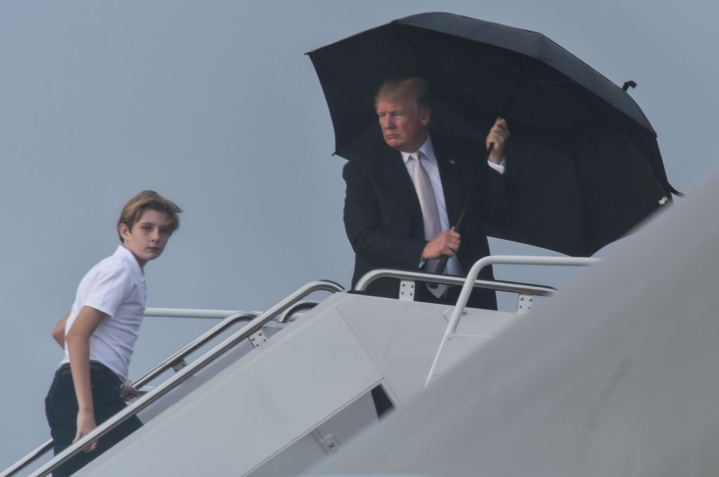 US President Donald Trump holds an umbrella as he waits for his son Barron and wife Melania to board Air Force One at Palm Beach International Airport in West Palm Beach