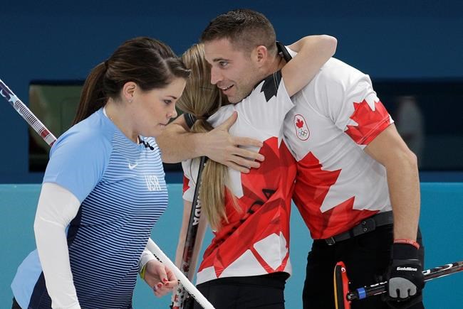 Canada's Kaitlyn Lawes center and John Morris right embrace as United States Becca Hamilton passes by after their mixed doubles curling match at the 2018 Winter Olympics in Gangneung South Korea Thursday Feb. 8 2018