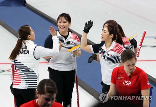 South Korea's women's curling team high-fives after winning a round-robin match against the United States at the Gangneung Curling Center during the Pyeong Chang Winter Olympics on Feb. 20 2018