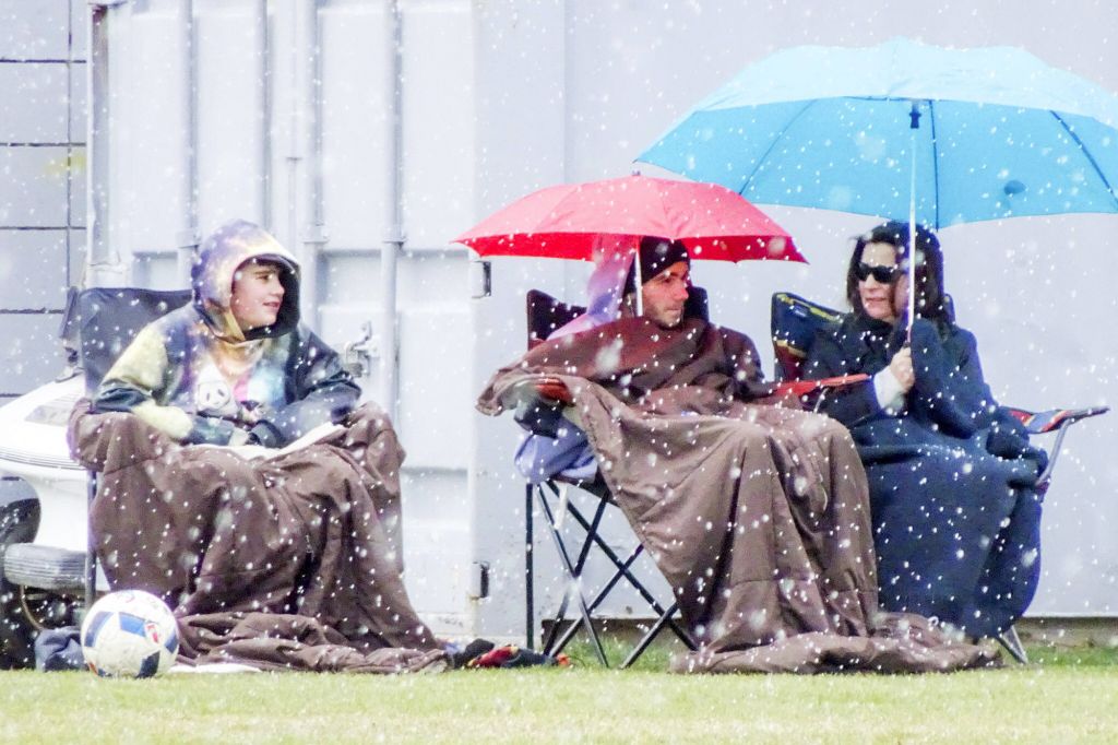 Fans on the sidelines on a Penticton Pinnacles soccer game shiver through the snow on April 1