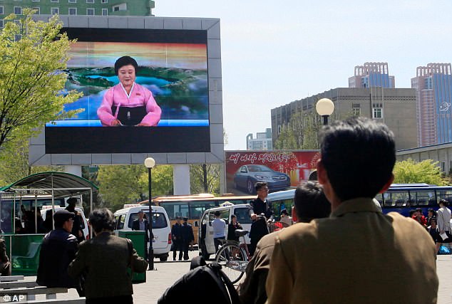 North Koreans watch as their country's most famous newscaster announces leader Kim Jong Un's proposal to suspend nuclear tests and long-range missile launches on a giant screen on Pyongyang's newly built Mirae Scientists Street